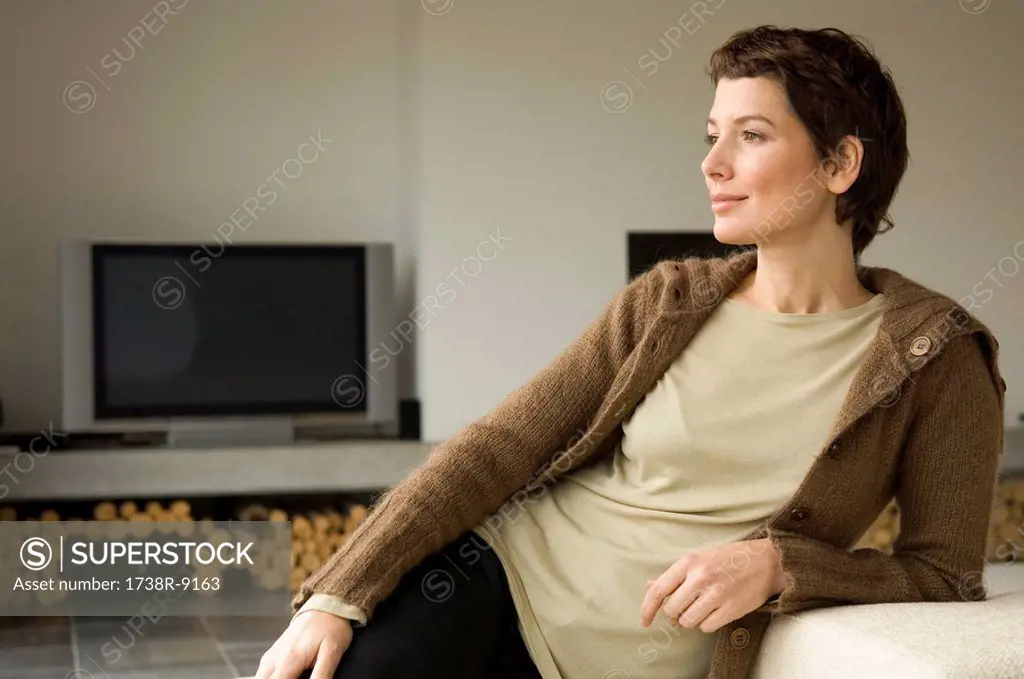 Mid adult woman leaning against a couch