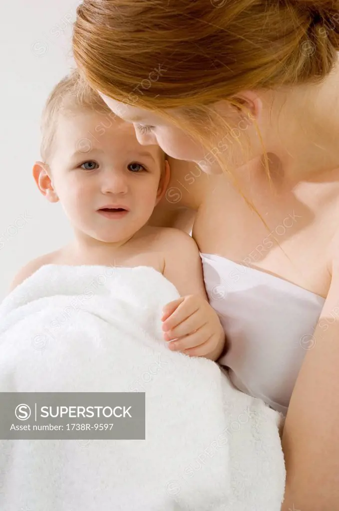 Close_up of a young woman wrapping her son in a towel