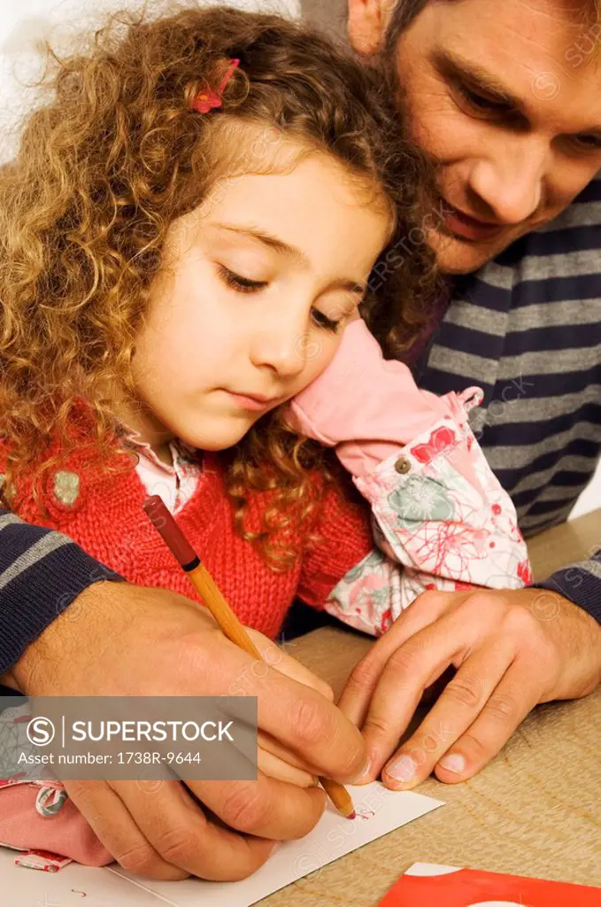 Mid adult man helping his daughter in drawing
