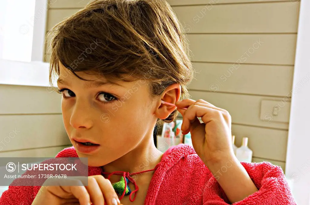 Portrait of a boy cleaning his ear with a cotton swab