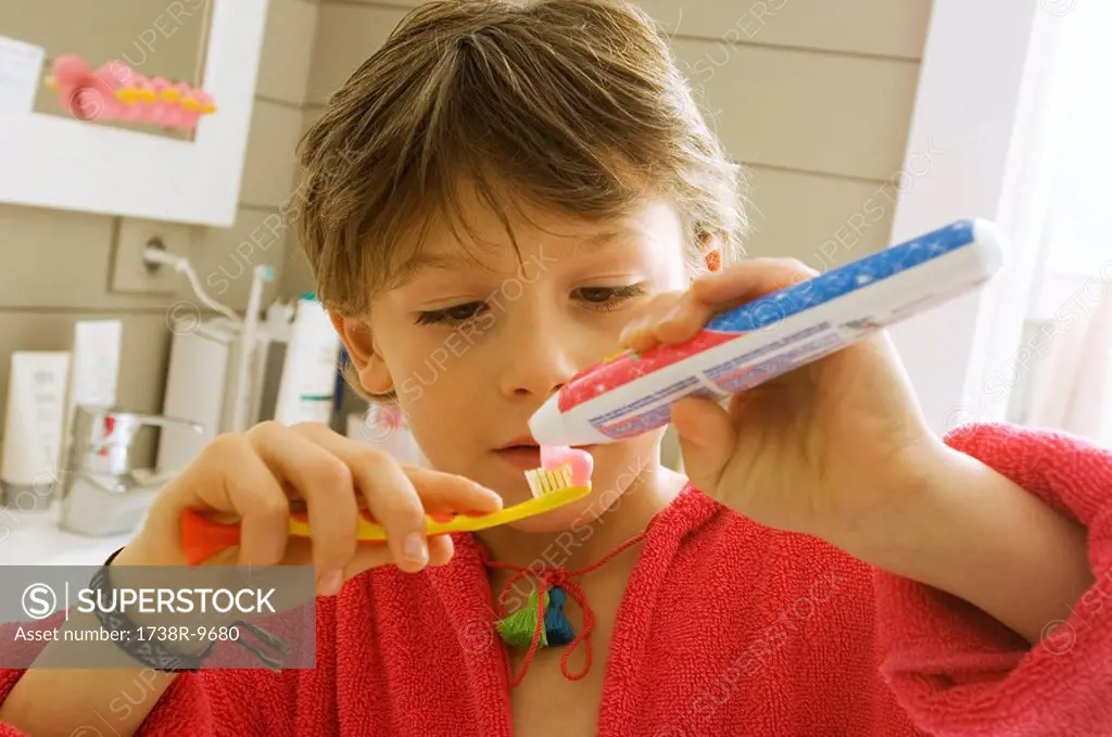 Close_up of a boy holding a toothpaste and a toothbrush