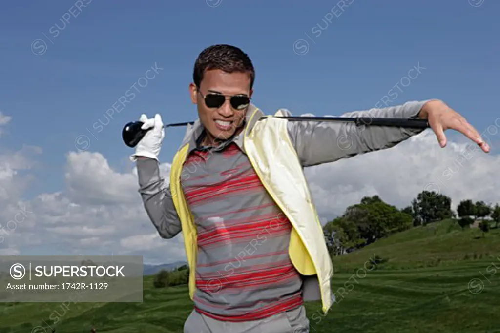 Man wearing shades posing with a  golf club over his shoulders