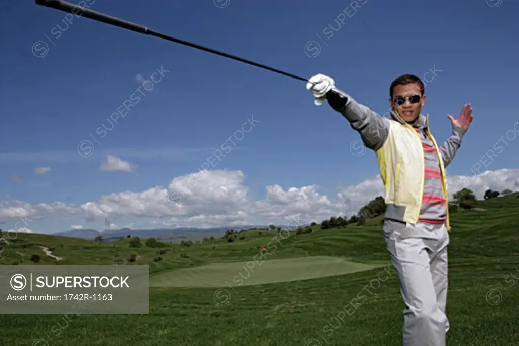 Portrait of a young man posing with a golf club.