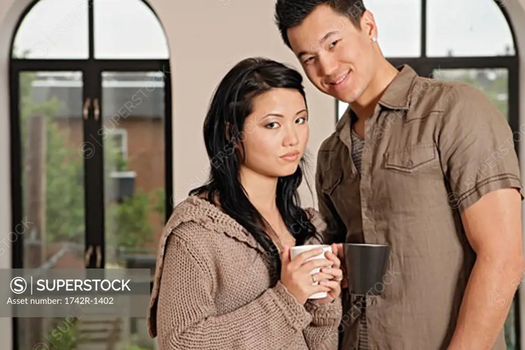 Young couple holding cups, portrait