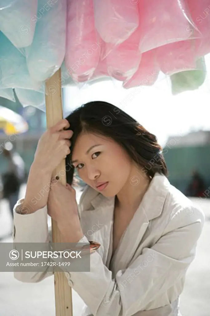Asian woman leaing on a pole holding cotton candy