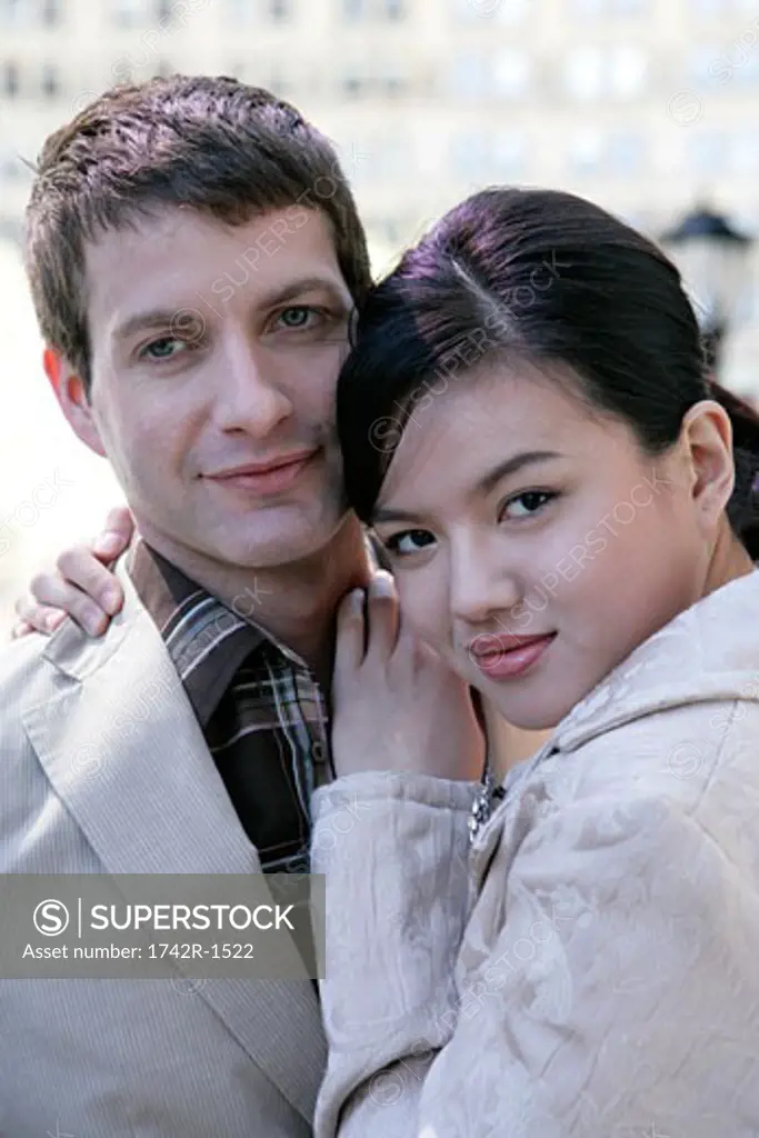 Interracial  couple embracing looking at camera