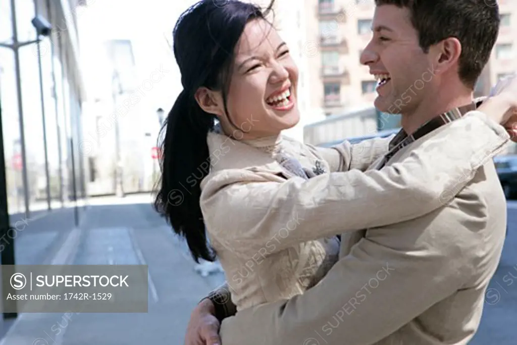 Interracial couple embracing having fun outdoors