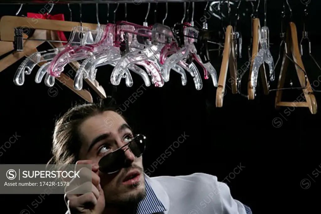 Young man standing beneath a row of hangers