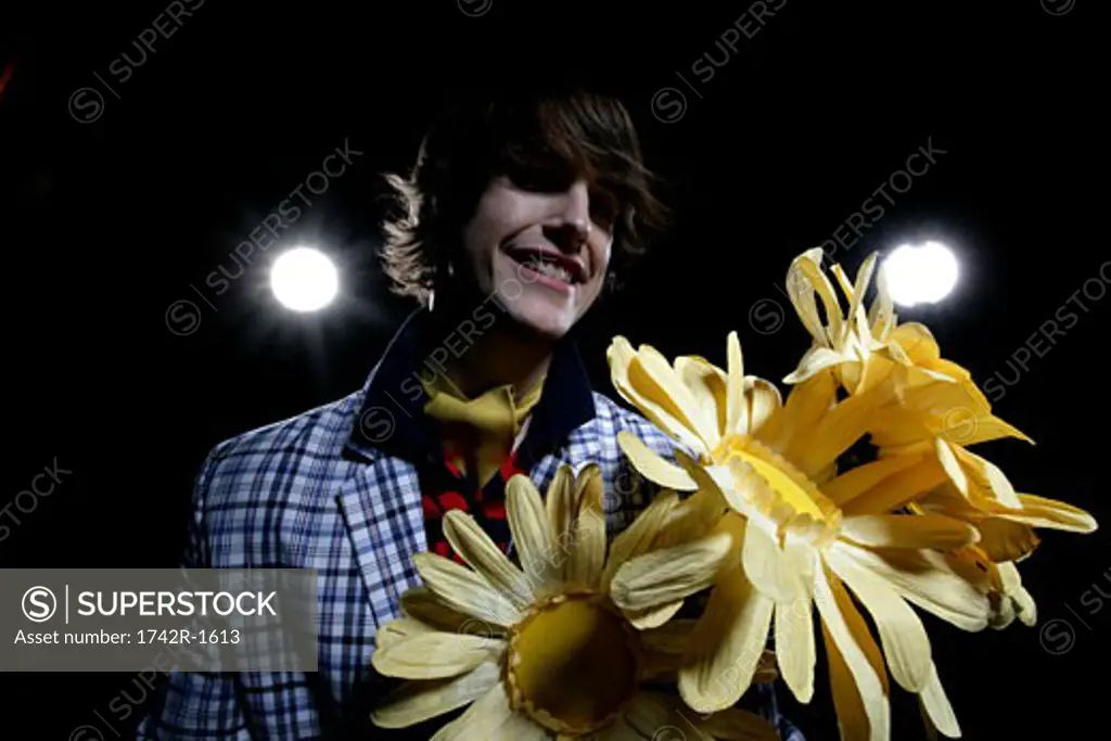 Young man holding large paper sunflowers