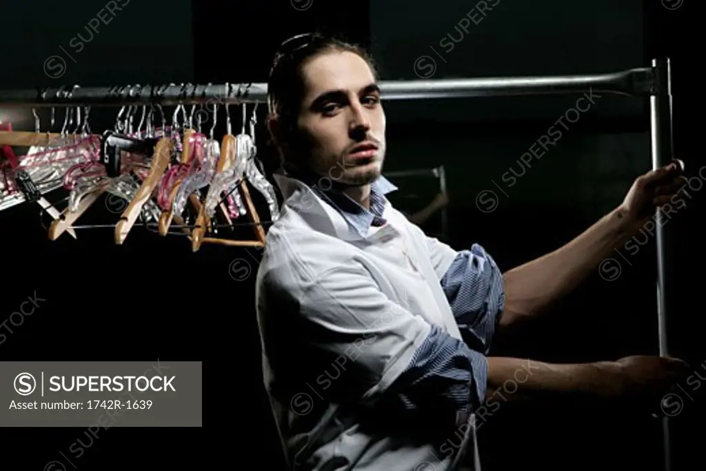 Young man holding a clothing rack