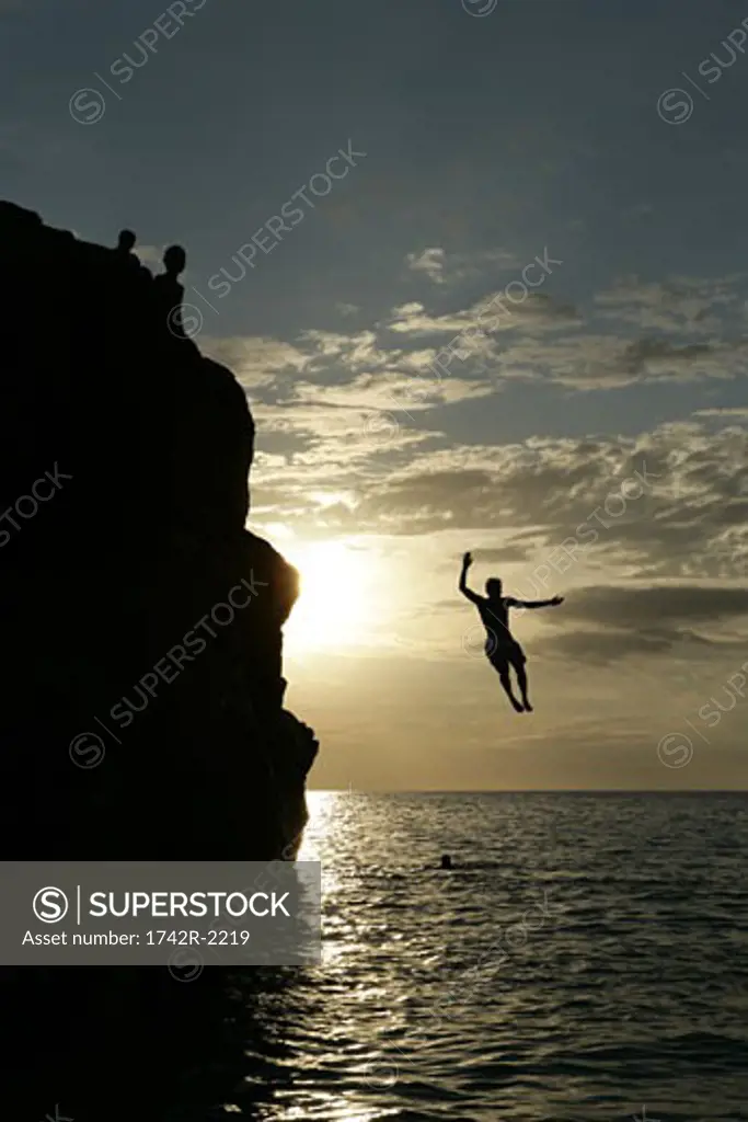 People are jumping from a cliff into the sea.
