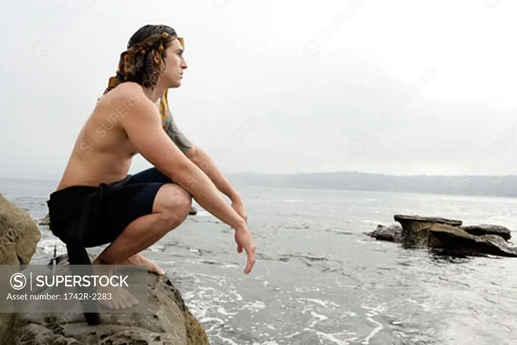 View of a young man sitting on a rock.