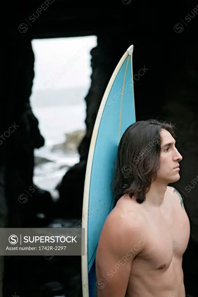 View of a man holding a surfboard.