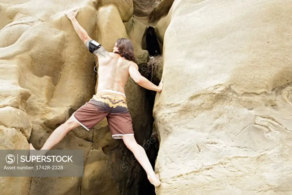 View of a young man rock climbing.