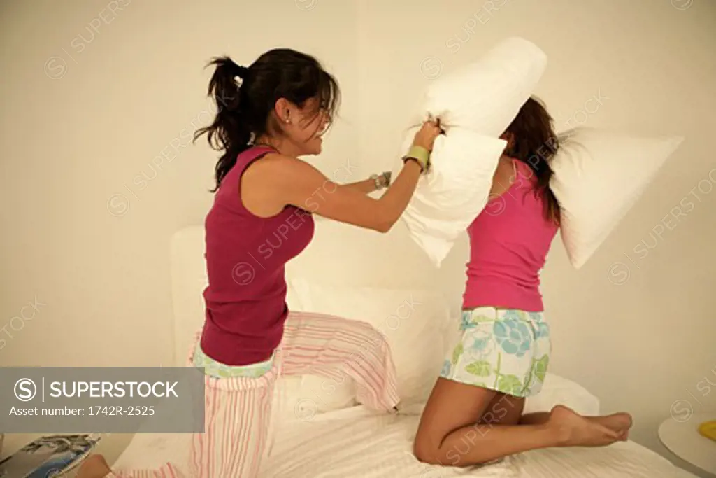 Two females engage in a pillow fight.