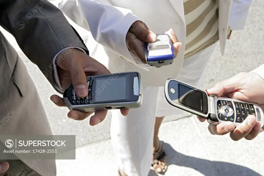 Three people are holding their cellphones.