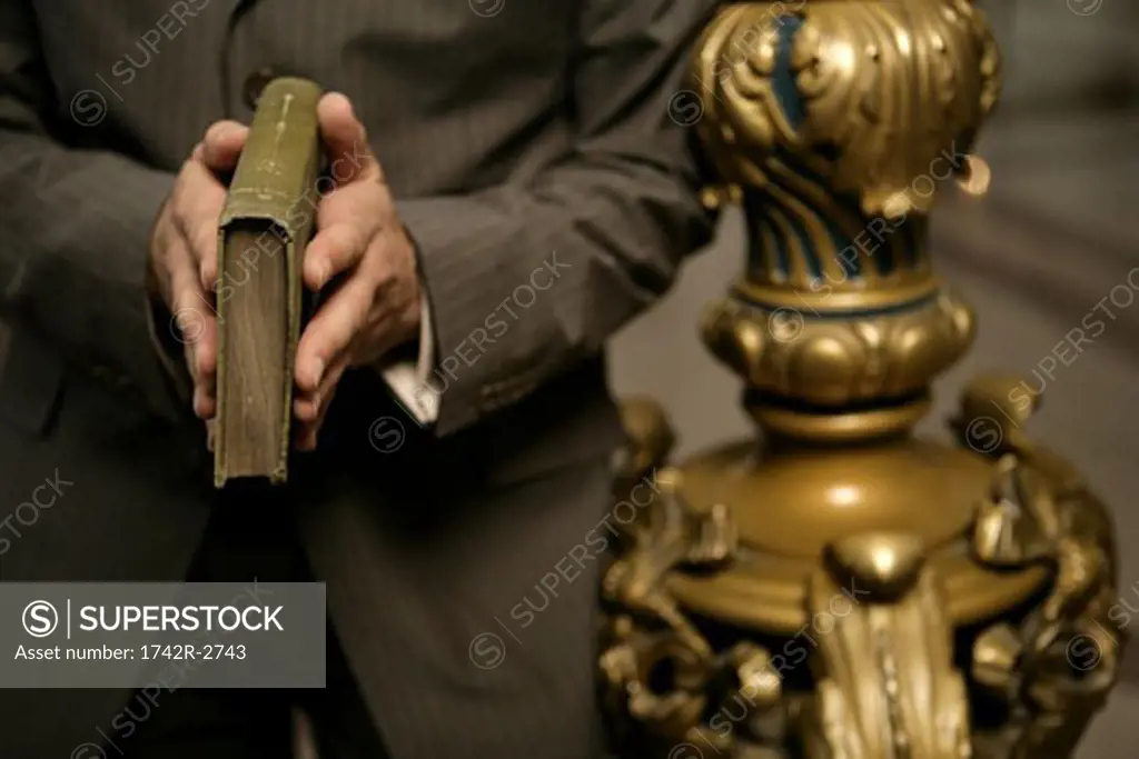Midsection of a man holding a book.