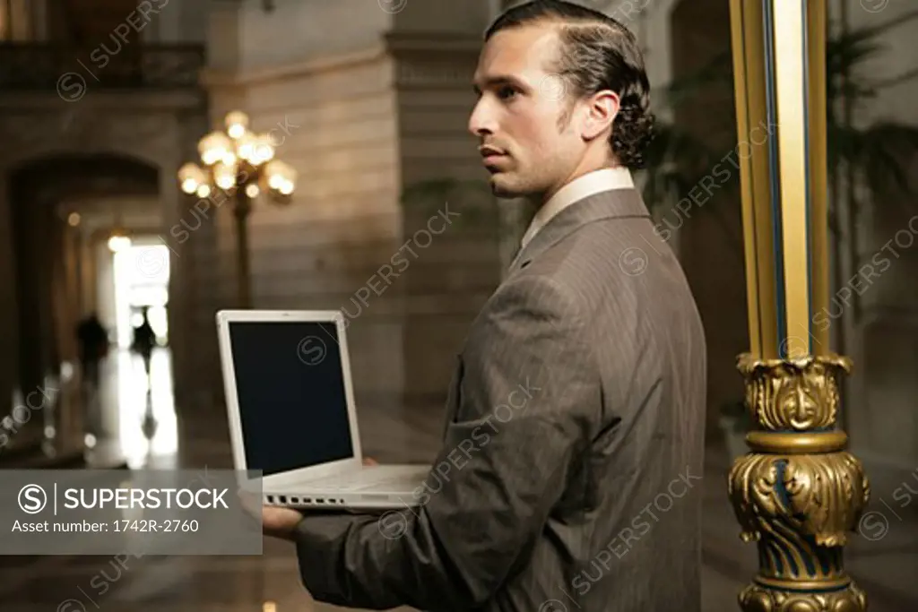 View of a businessman holding a laptop.