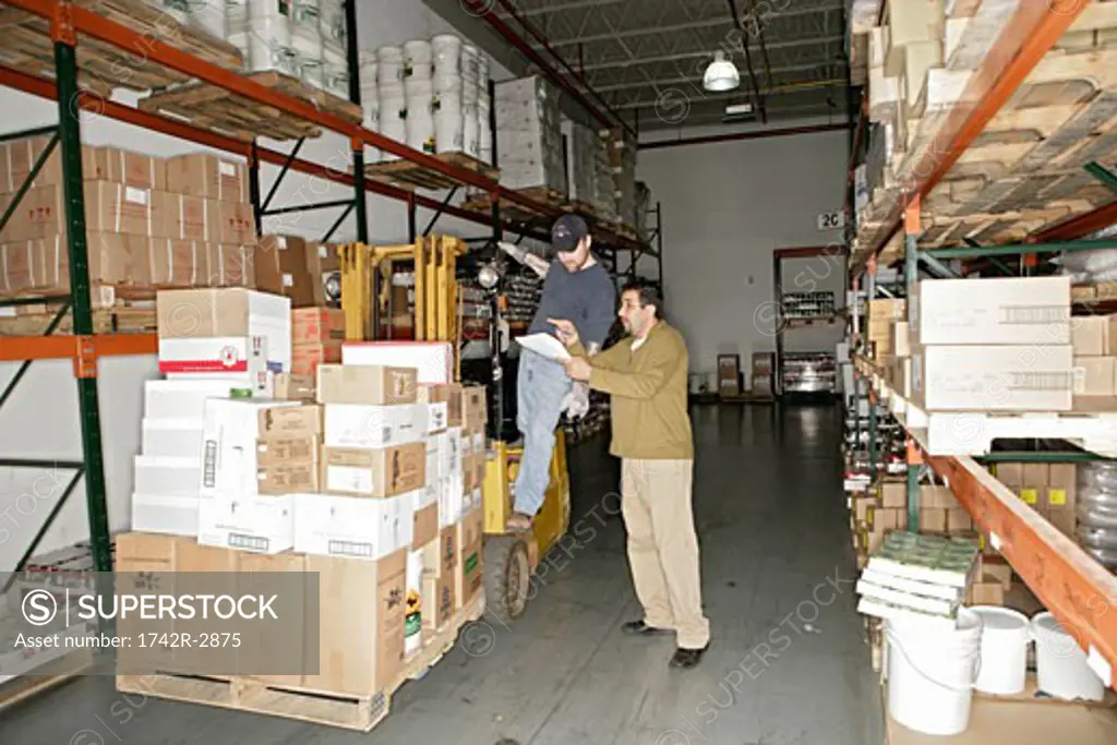 View of two men working inside a warehouse.