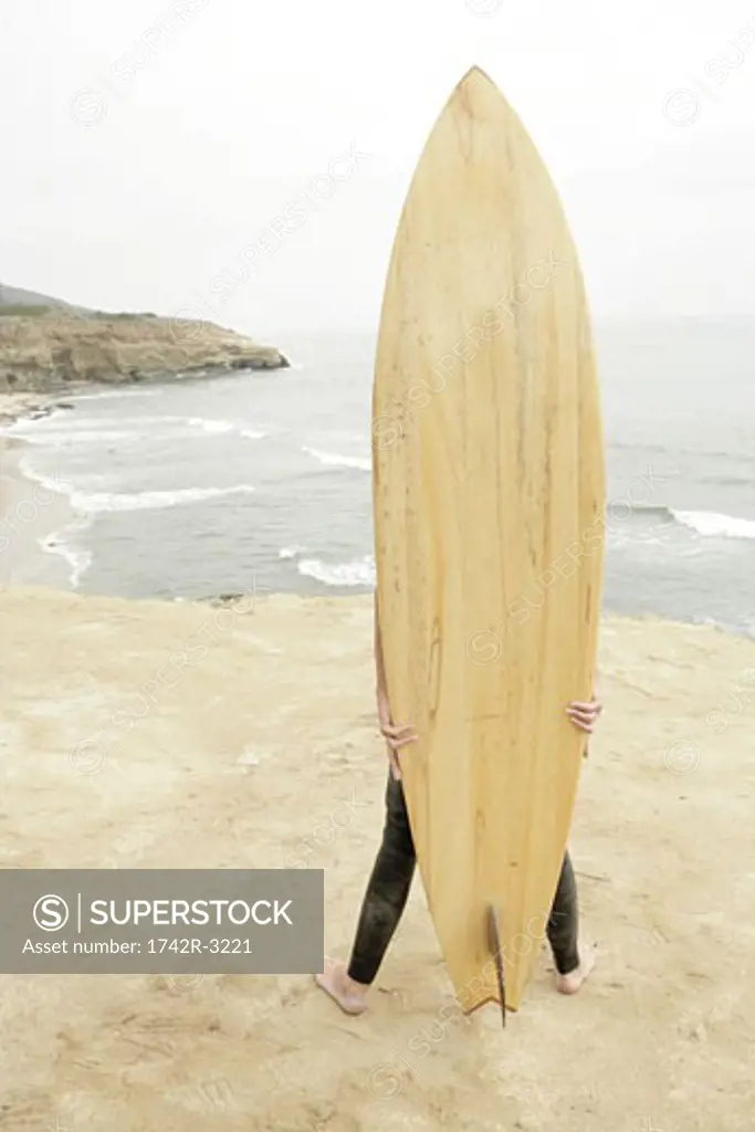 View of a person hidden with a surfboard.