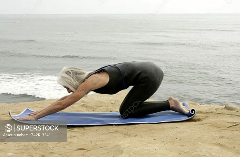 View of a woman stretching out near a sea.