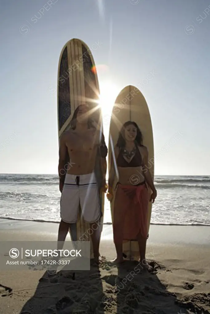 View of a couple standing with surfboards.