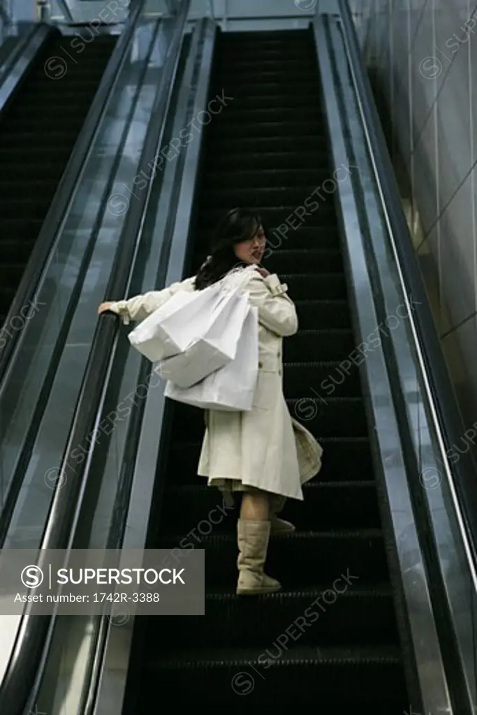 A young woman is standing on an escalator.