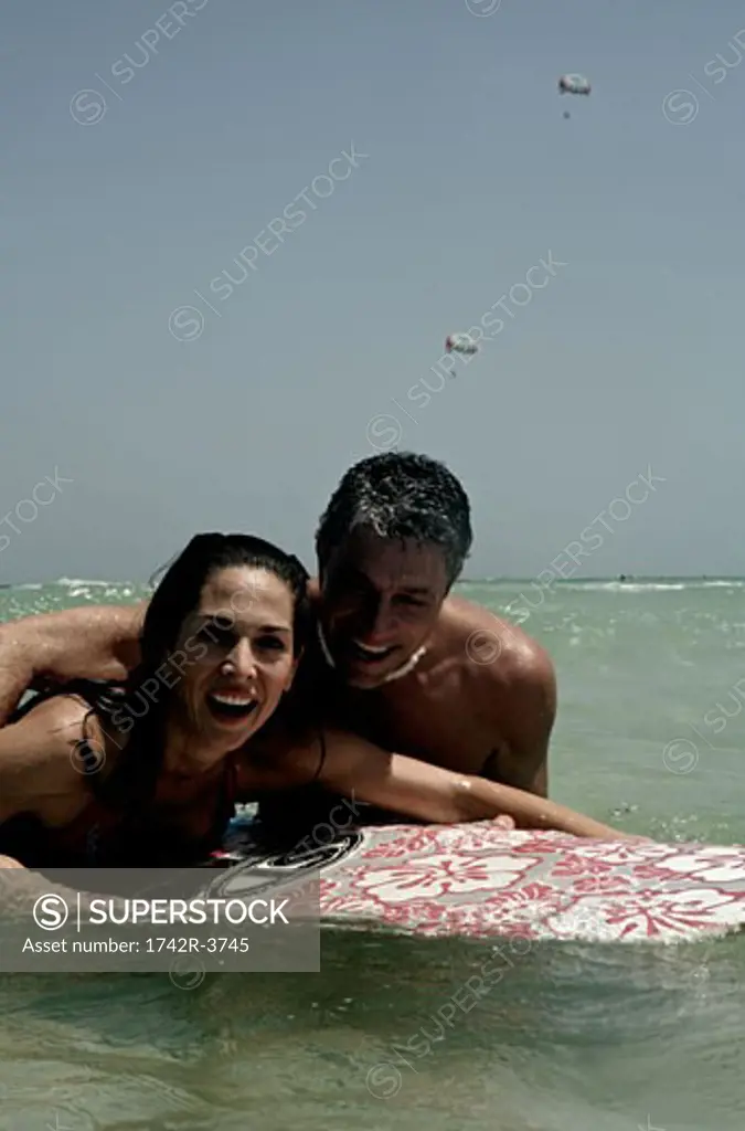 View of a couple surfboarding in the sea.