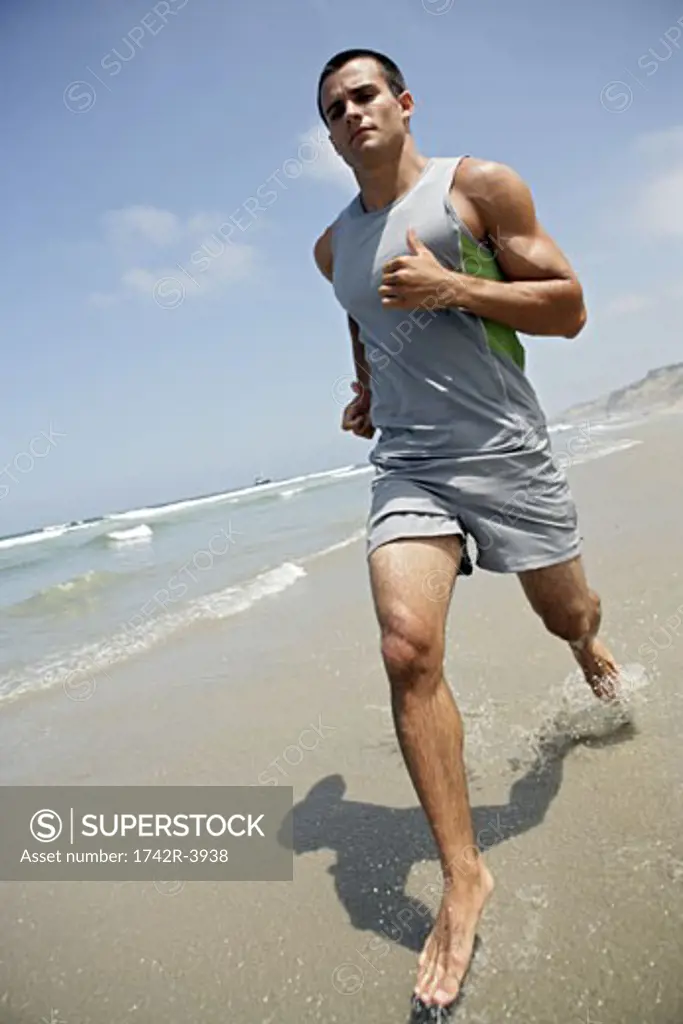 A young man is running on a beach.