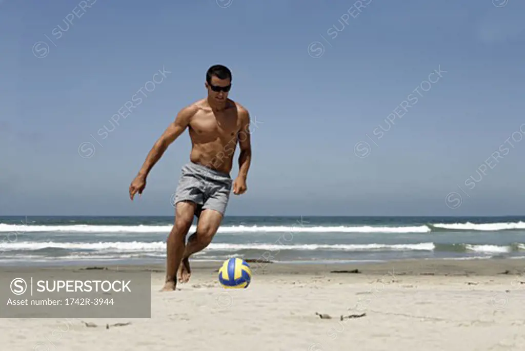 A young man is playing on the beach.