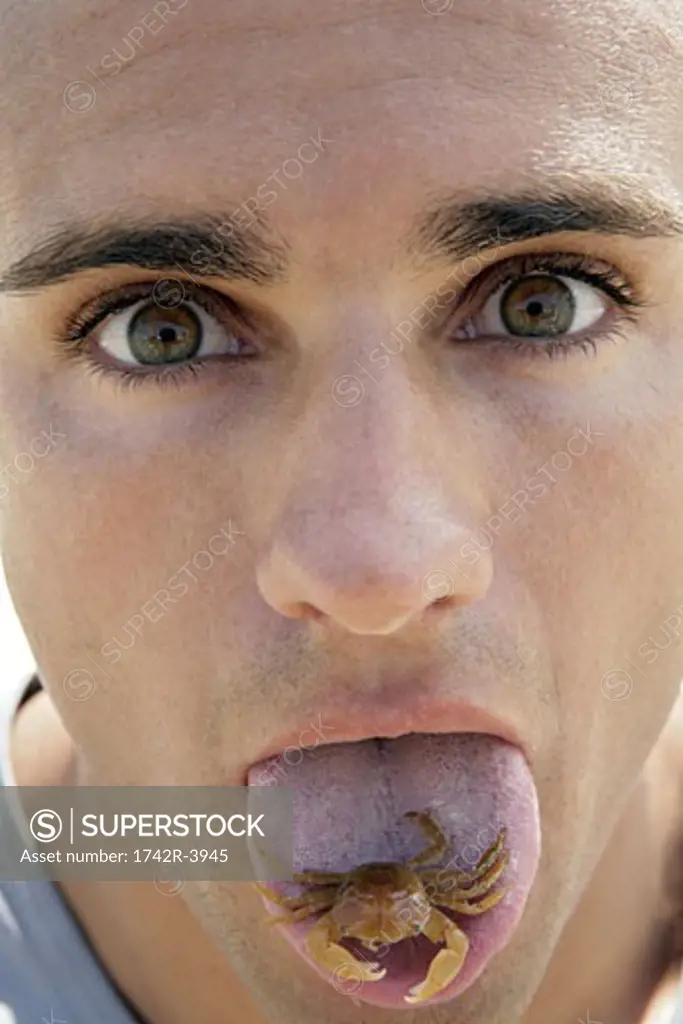 Portrait of a young man with a tiny crab on his tongue.