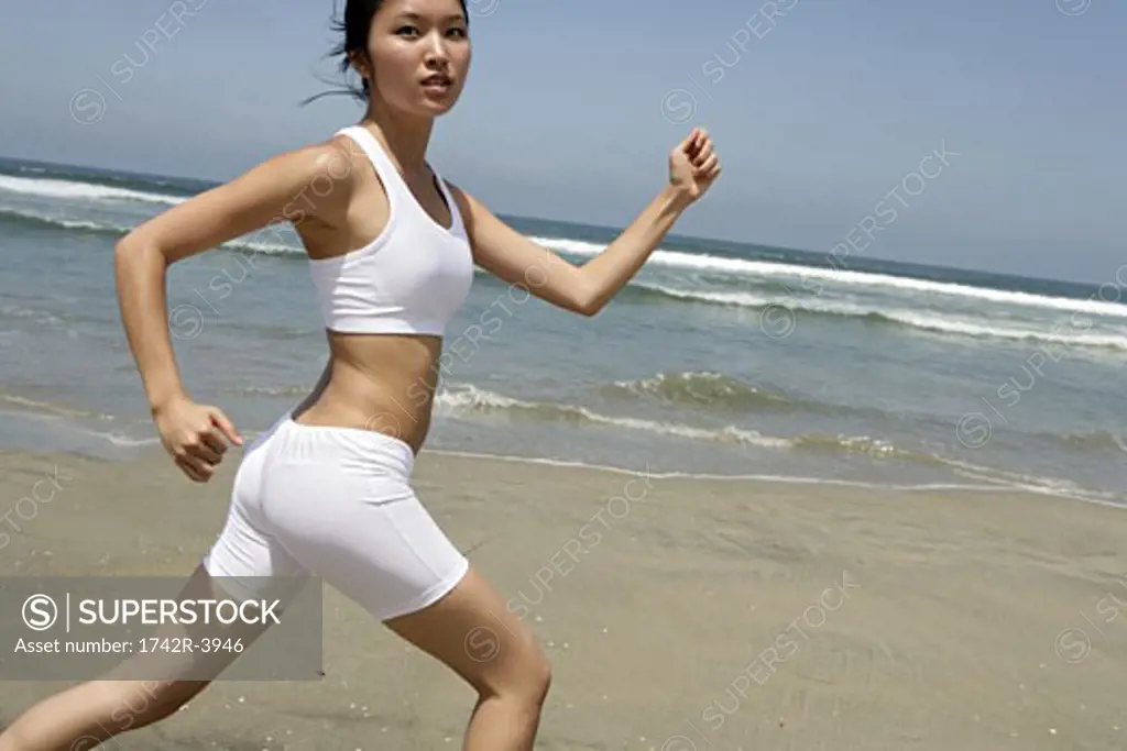 A young woman is running on a beach.