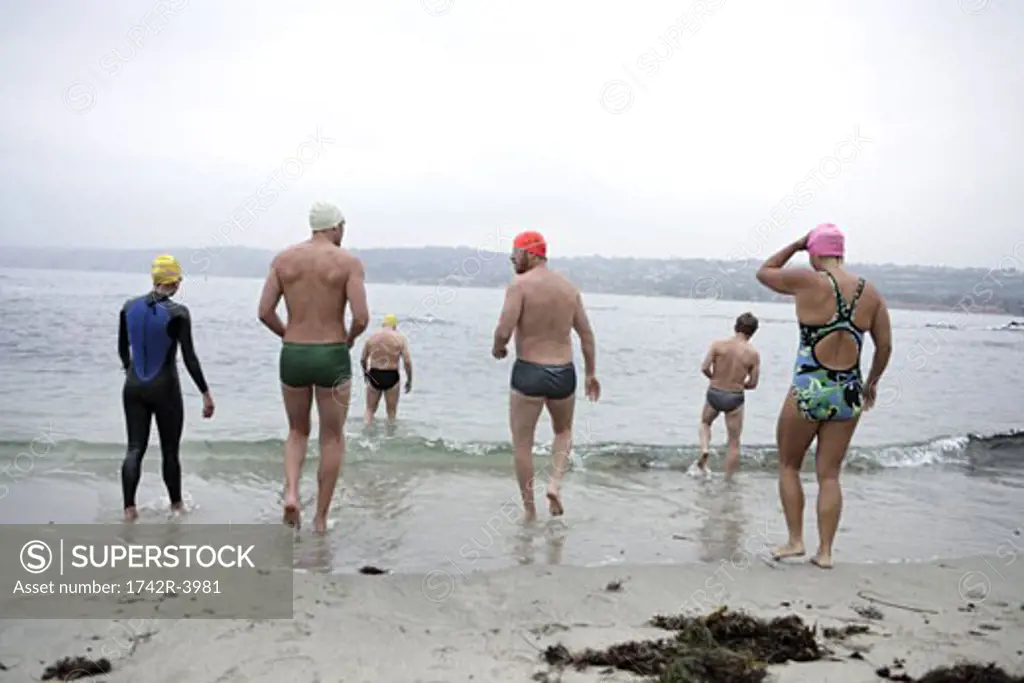 View of swimmers walking towards sea.