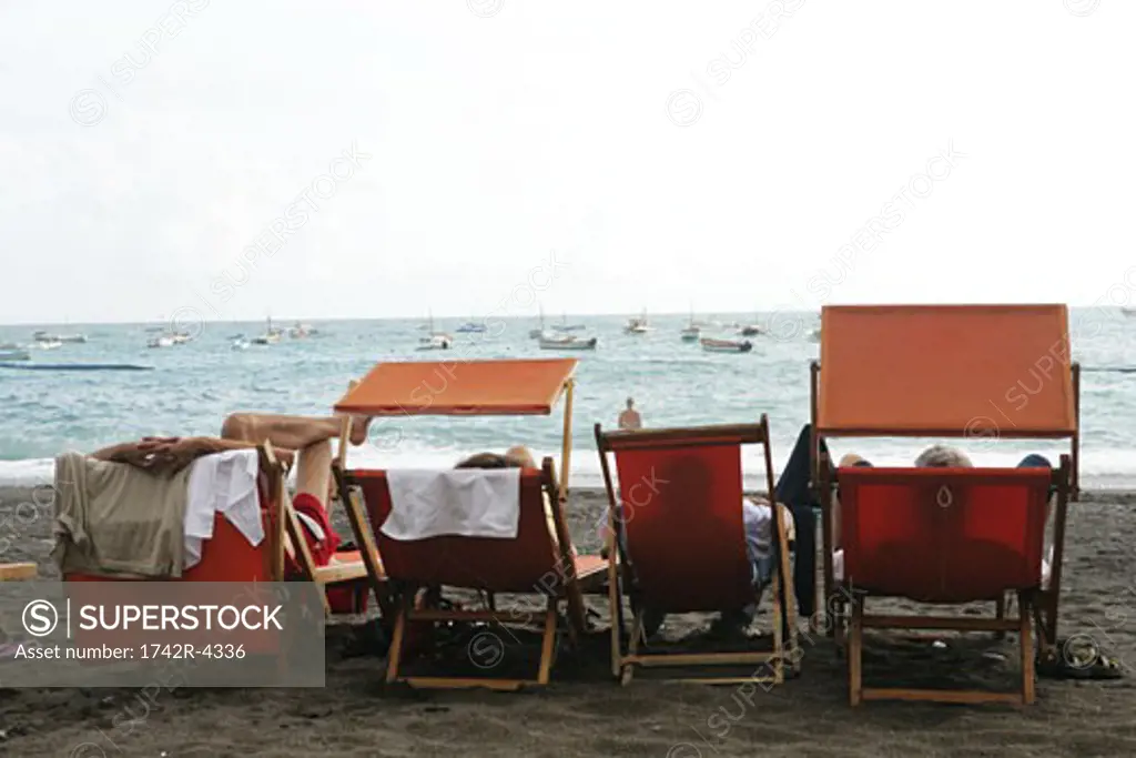 People relaxing on beach, rear view