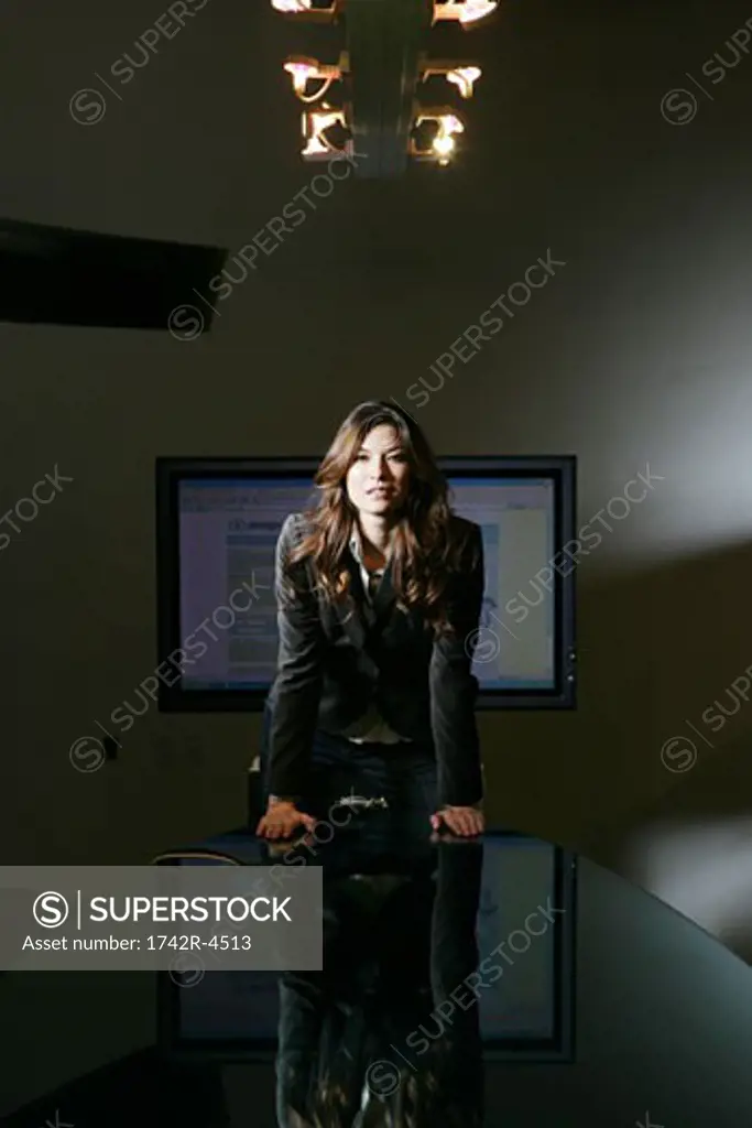 Woman in a conference room, leaning on the table