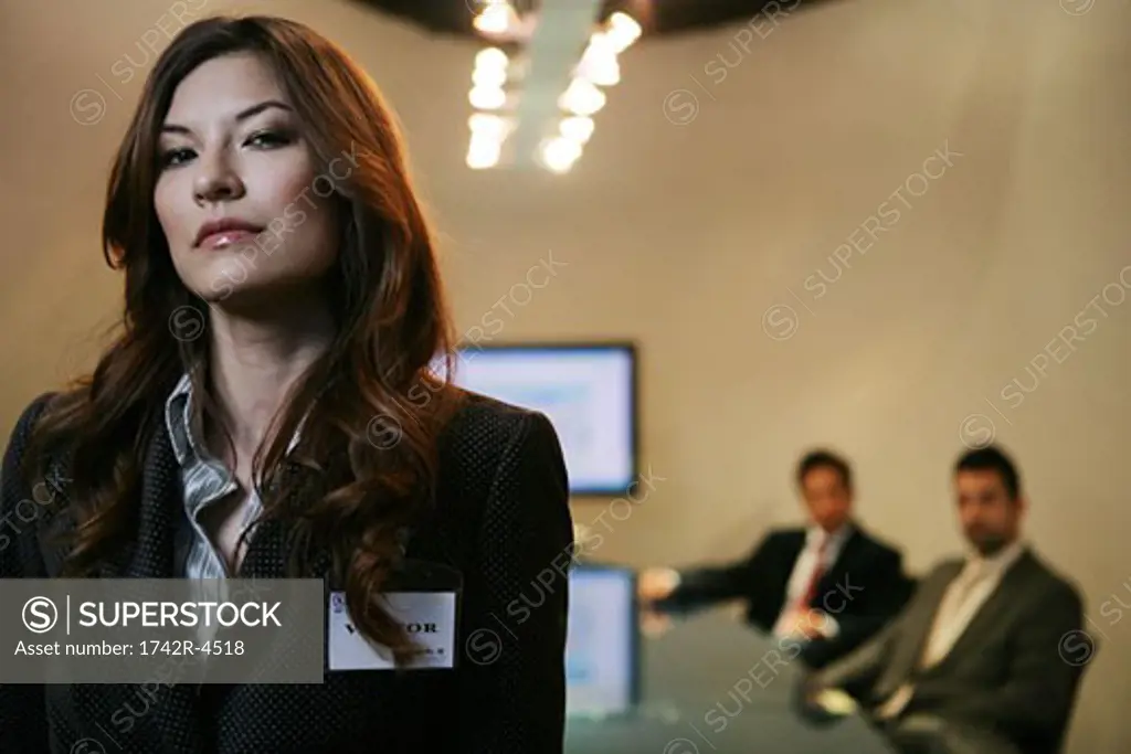 Three people inside a conference room, woman standing apart