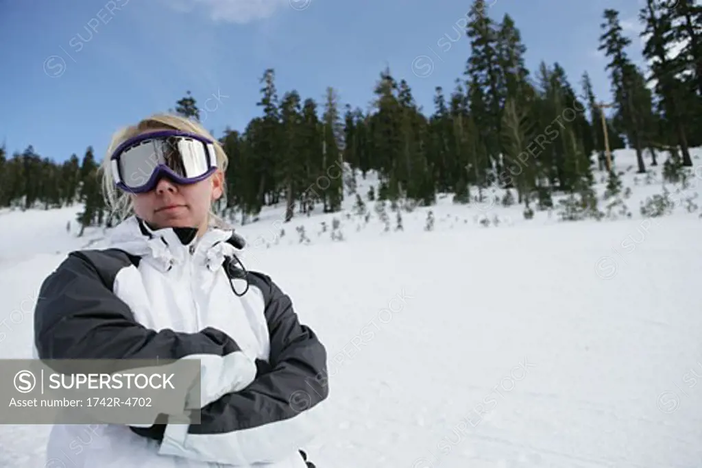 Woman standing on ski slope with her arms folded