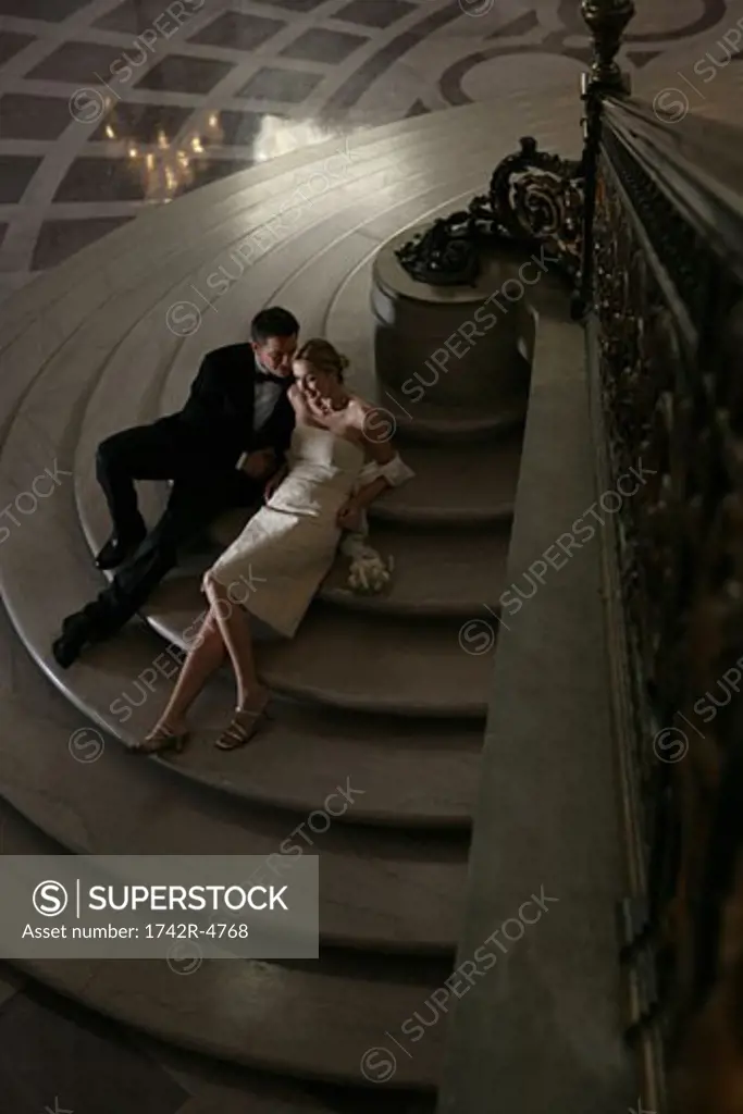 Couple sitting on step in formal attire