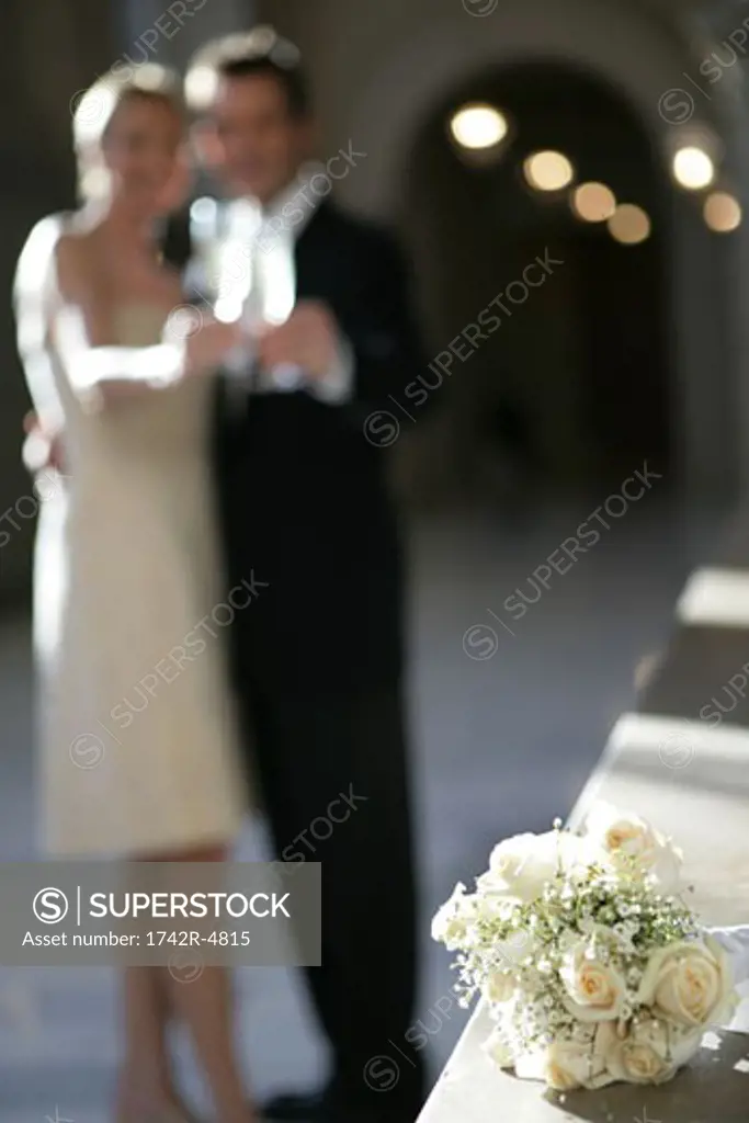 Couple drinking in background of a bouquet of roses