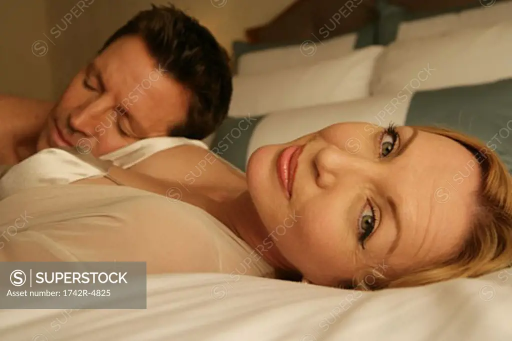 Mature couple in bed, woman looking at camera