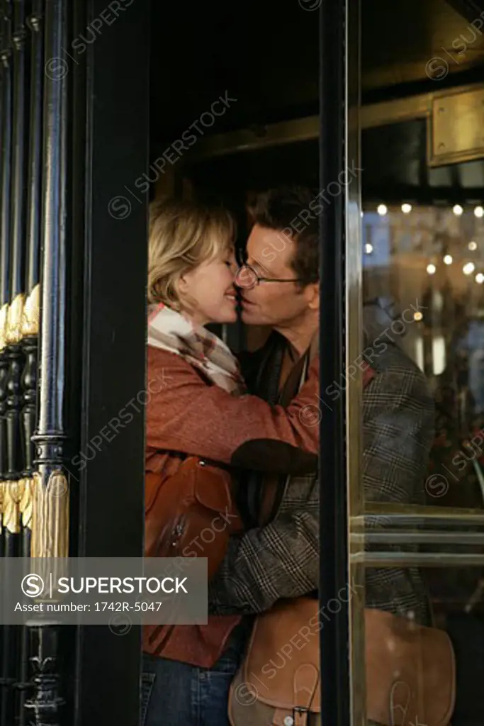 Mature couple kissing inside revolving doors