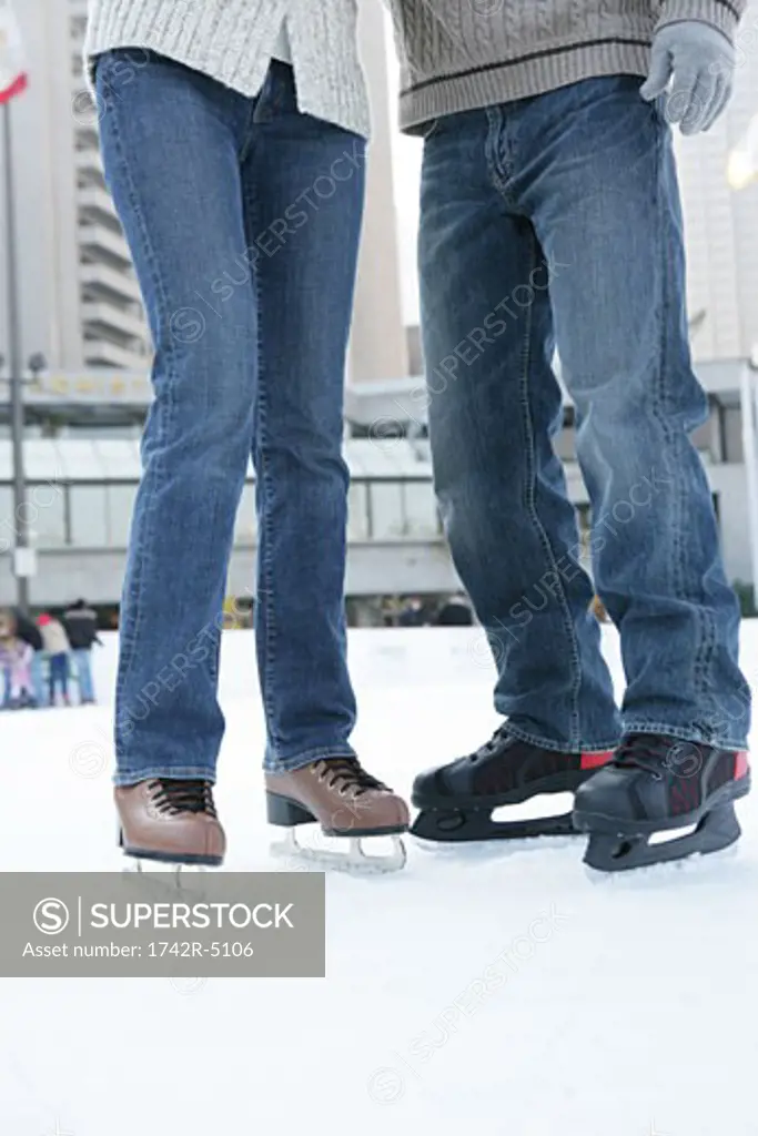 Man and a woman wearing jeans and ice skates