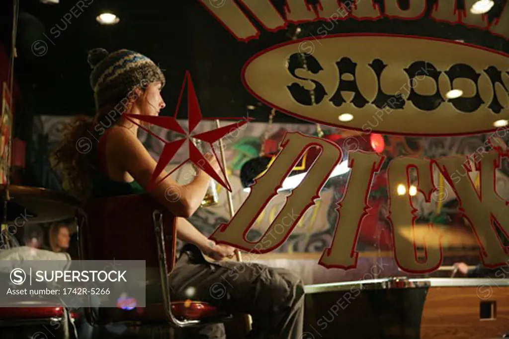 Woman sitting inside a pool hall holding a cue stick