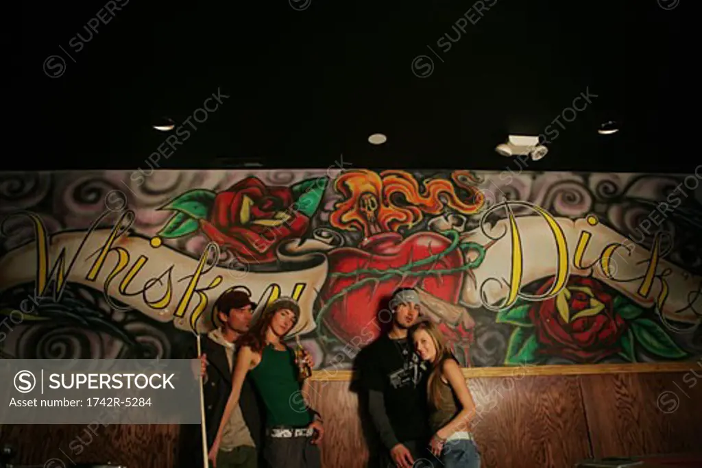 Two couples standing in front of a mural in a pool hall
