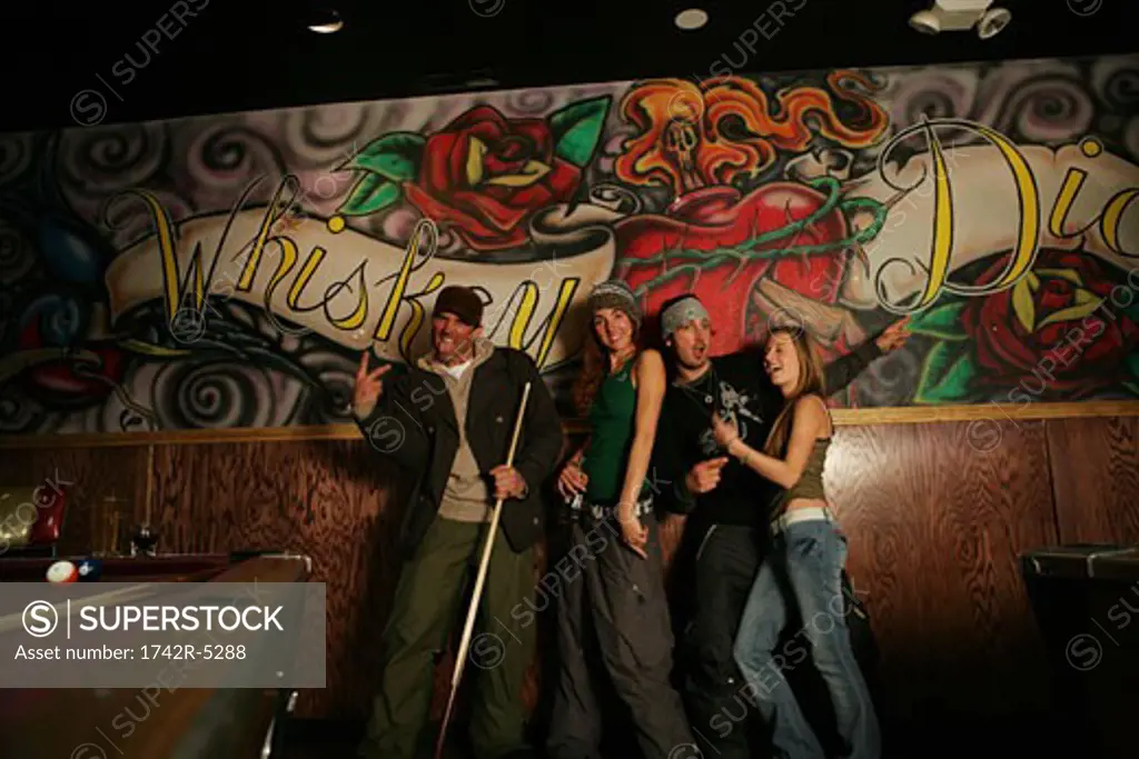 Four people standing in front of a mural in a pool hall