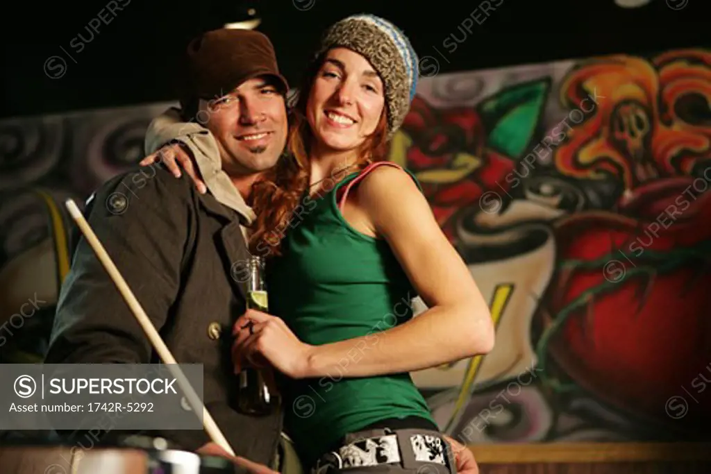 Couple looking at camera smiling in a pool hall