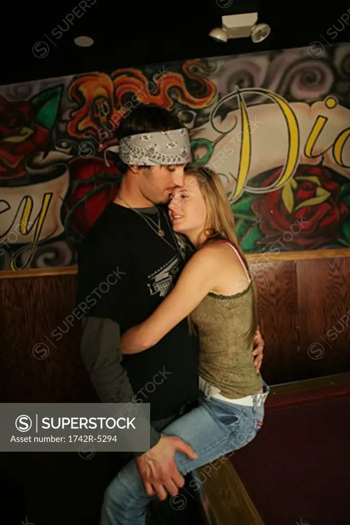 Woman sitting on a pool table hugging a man