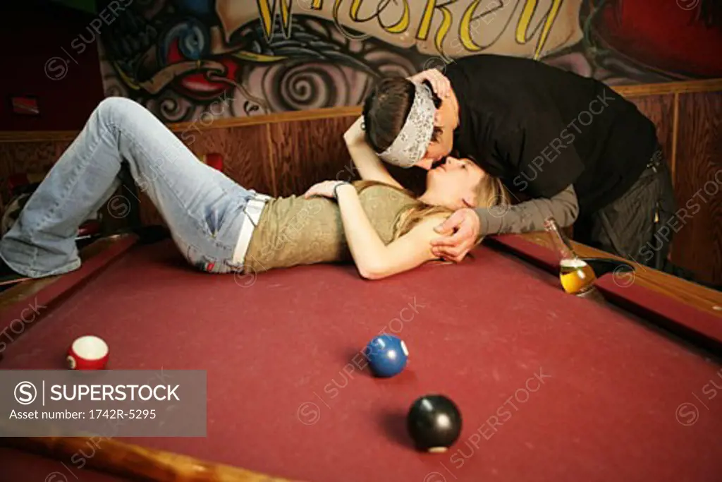 Couple kissing on a pool table
