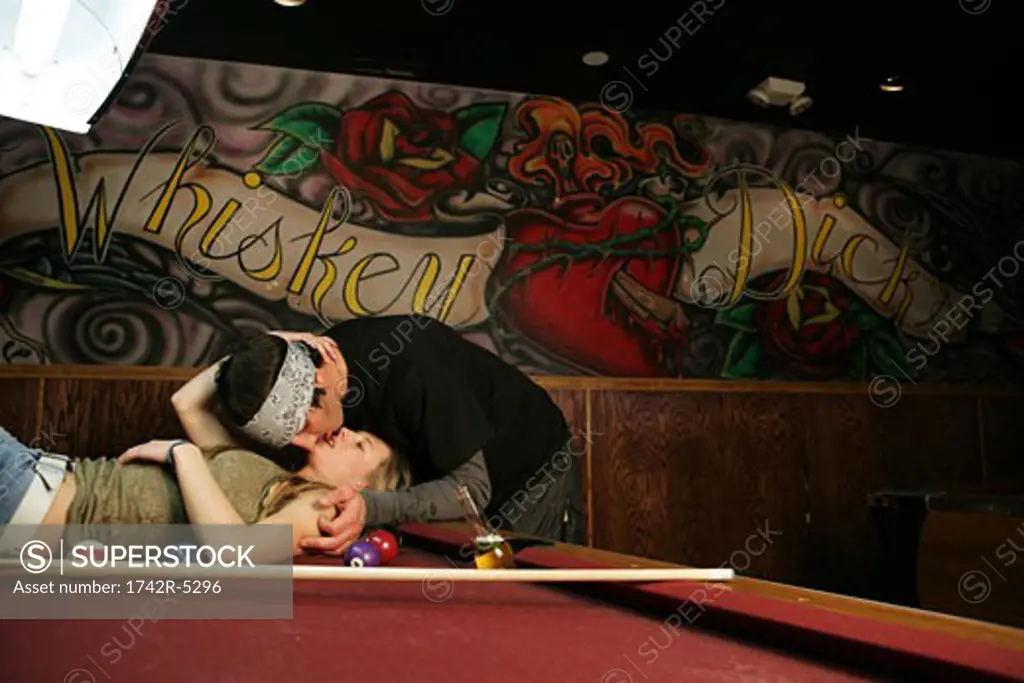 Couple kissing on a pool table