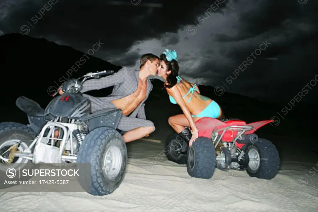 Young couple kissing on ATVs